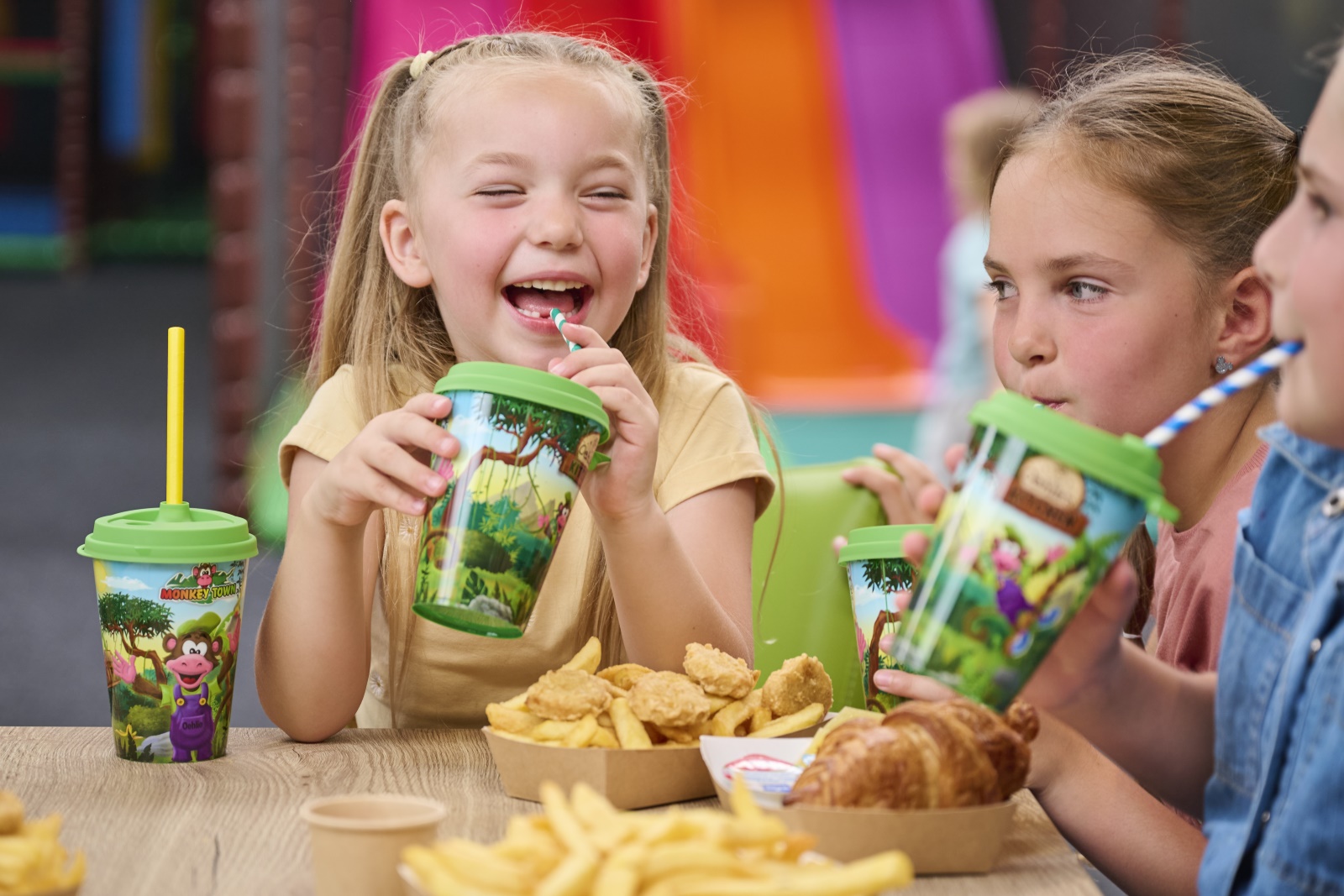 Kinderen poseren samen met Oehlie, de mascotte van Monkey Town, in kleurrijke kleding