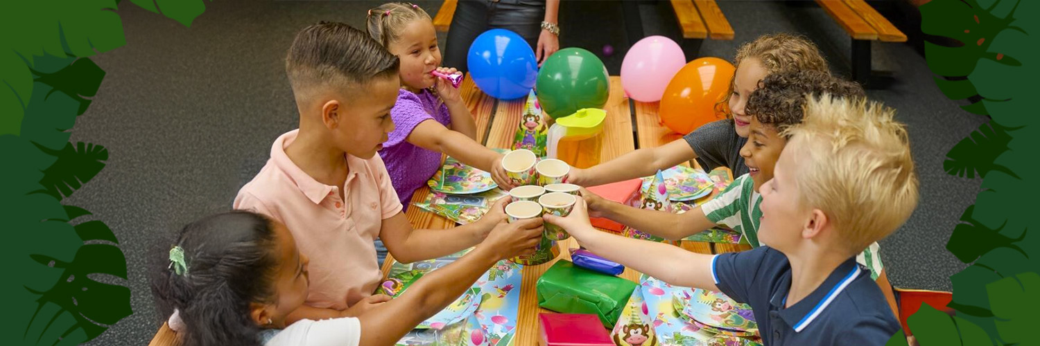 Kinderen vieren kinderfeestje bij Monkey Town met versierde tafel en feestelijke bekers