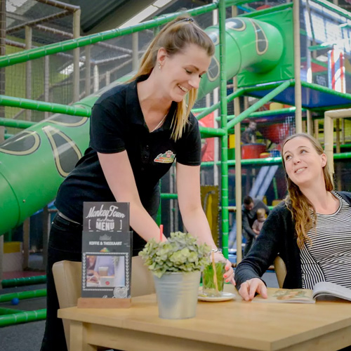 Medewerkster van Monkey Town in gesprek met bezoeker in de speelhal