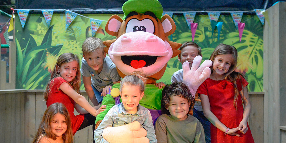 Kinderen op schoolreisje bij Monkey Town poseren met mascotte Oehlie